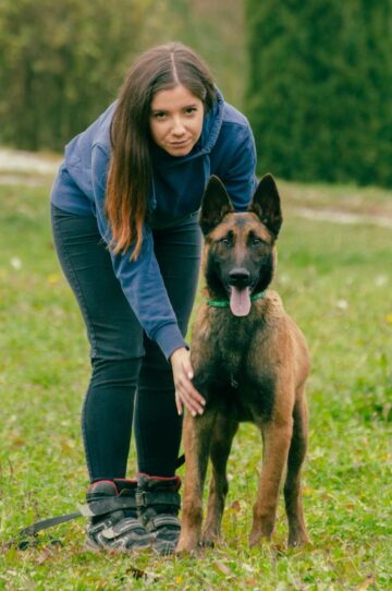 woman in blue jacket standing near a dog