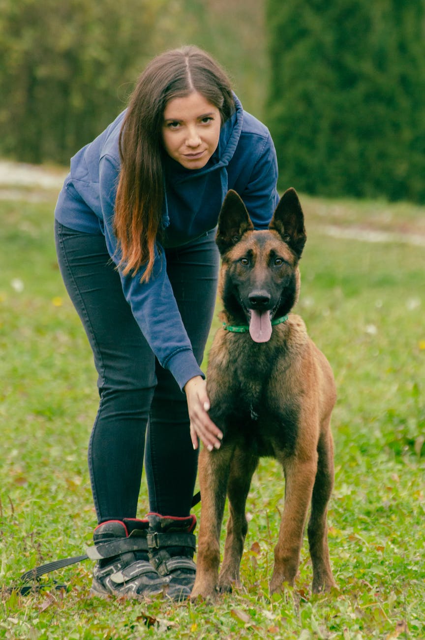 woman in blue jacket standing near a dog